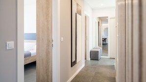 A modern hotel hallway with a bed, artwork, and a seating area.