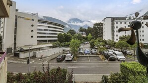Ein Parkplatz mit Autos, ein Gebäude mit bogenförmiger Fassade und Berge im Hintergrund.