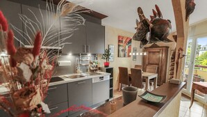 Eine moderne Küche mit grauen Schränken, einer Holzausziehtischplatte und einem Essbereich mit Tisch und Stühlen.
