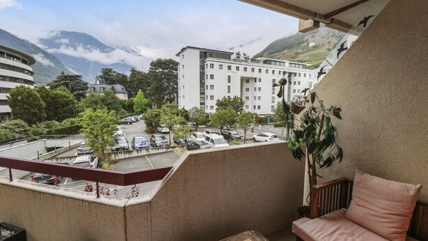 Ein Balkon mit Blick auf einen Parkplatz und ein mehrstöckiges Gebäude.