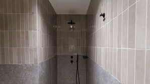 Een douche met een handdouche en een kraan op de muur.