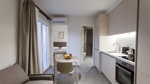 Een moderne keuken met een inbouwoven, een eethoek met een tafel en stoelen, en een bank.