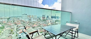 A balcony with a view of a cityscape, a table, and a chair. - Ong Kim Wee Residence (Malacca City)
