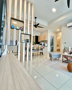 Uma sala de estar moderna com piso de madeira, uma área de jantar com mesa e cadeiras de madeira, e uma cozinha com armários de madeira.