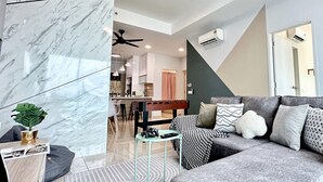 A modern living room with a marble wall, a grey sofa with patterned cushions, a coffee table, and a ceiling fan. - Ong Kim Wee Residence (Malacca City)
