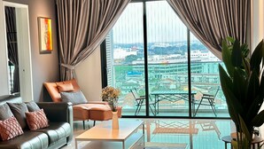 A modern living room with a sofa, coffee table, and a view of a cityscape through large windows. - Ong Kim Wee Residence (Malacca City)