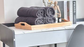 A neatly arranged workspace with a wooden tray holding rolled towels, a mannequin, and books on a marble desk.