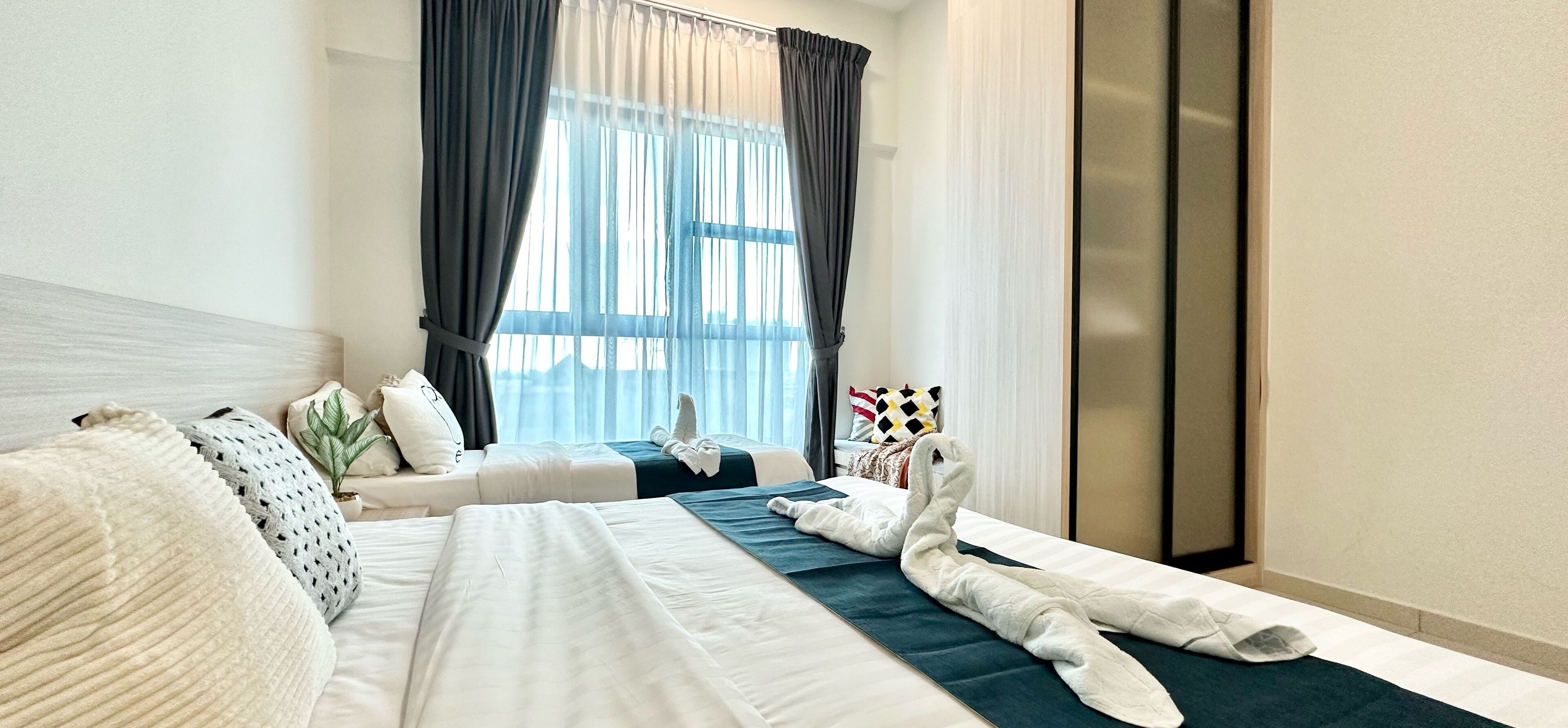 A hotel room with two beds, a large window with curtains, and a view of the city.