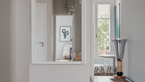 A hallway with a wooden floor, a white door, a mirror with an ornate frame, and a chandelier. - Wanderer's Retreat, by Veeve (Paris)