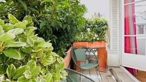 A balcony with potted plants, a chair, and a window with curtains. - Wanderer's Retreat, by Veeve (Paris)
