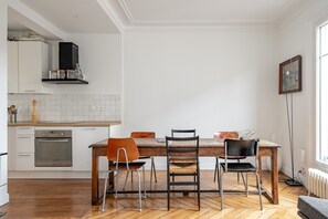 A modern kitchen with white cabinets, a wooden dining table, and two chairs. - Spire View, by Veeve (Paris)