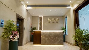 A reception area with a marble counter, a reception desk, and a large potted plant. - M2 Square by Monday Premium (Nagpur)