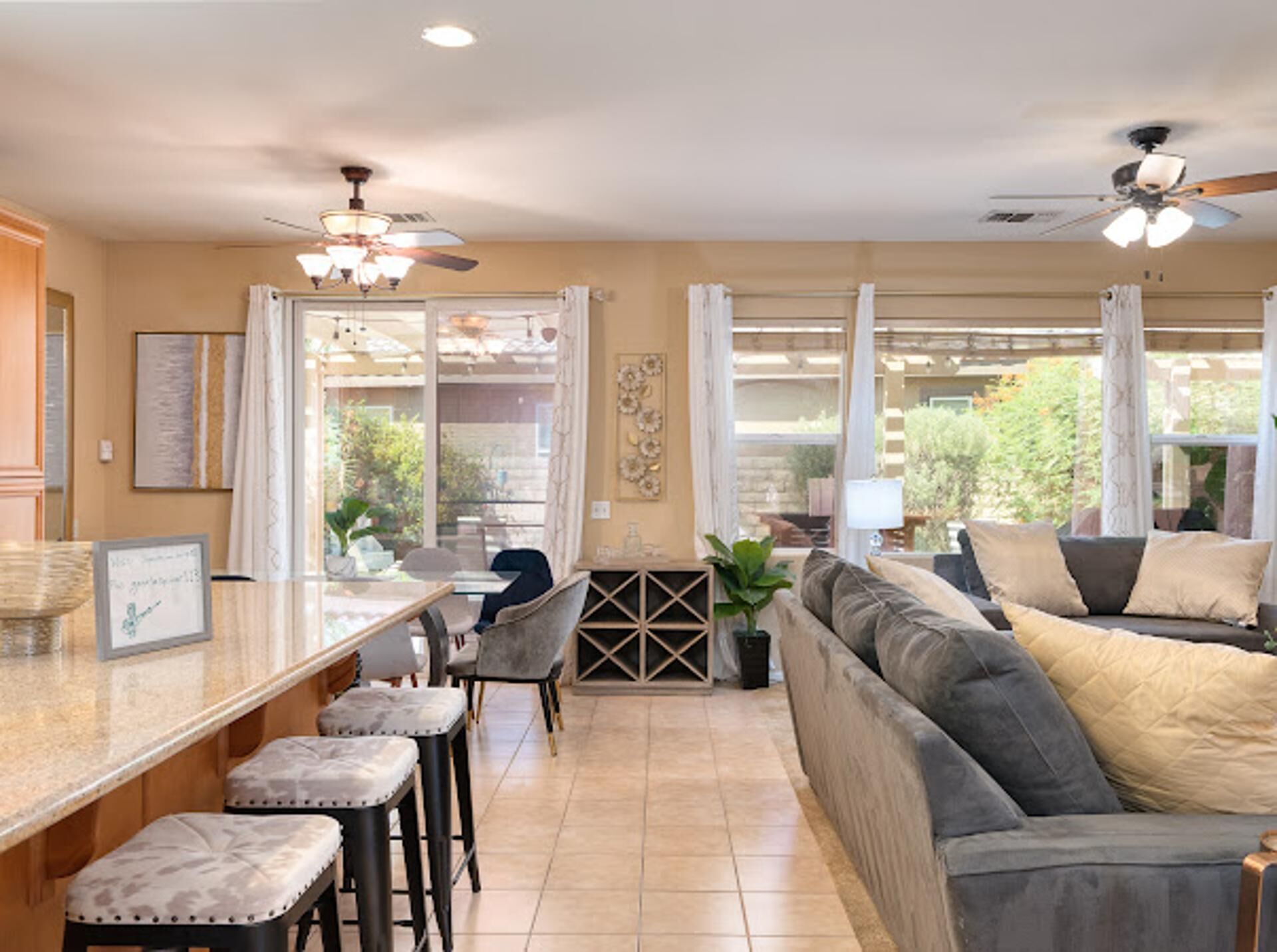 A modern kitchen with a central island, bar stools, a sofa, and a ceiling fan.