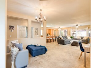 A spacious living room with a large sofa, ottoman, and a dining area with a table and chairs. - Stunning 4-bed House in Indio in Golf Course Commu (Indio)