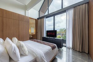 Una camera d'albergo con un letto grande, uno schermo TV che mostra 'NETFLIX' e vista all'aperto tramite ampie finestre.
