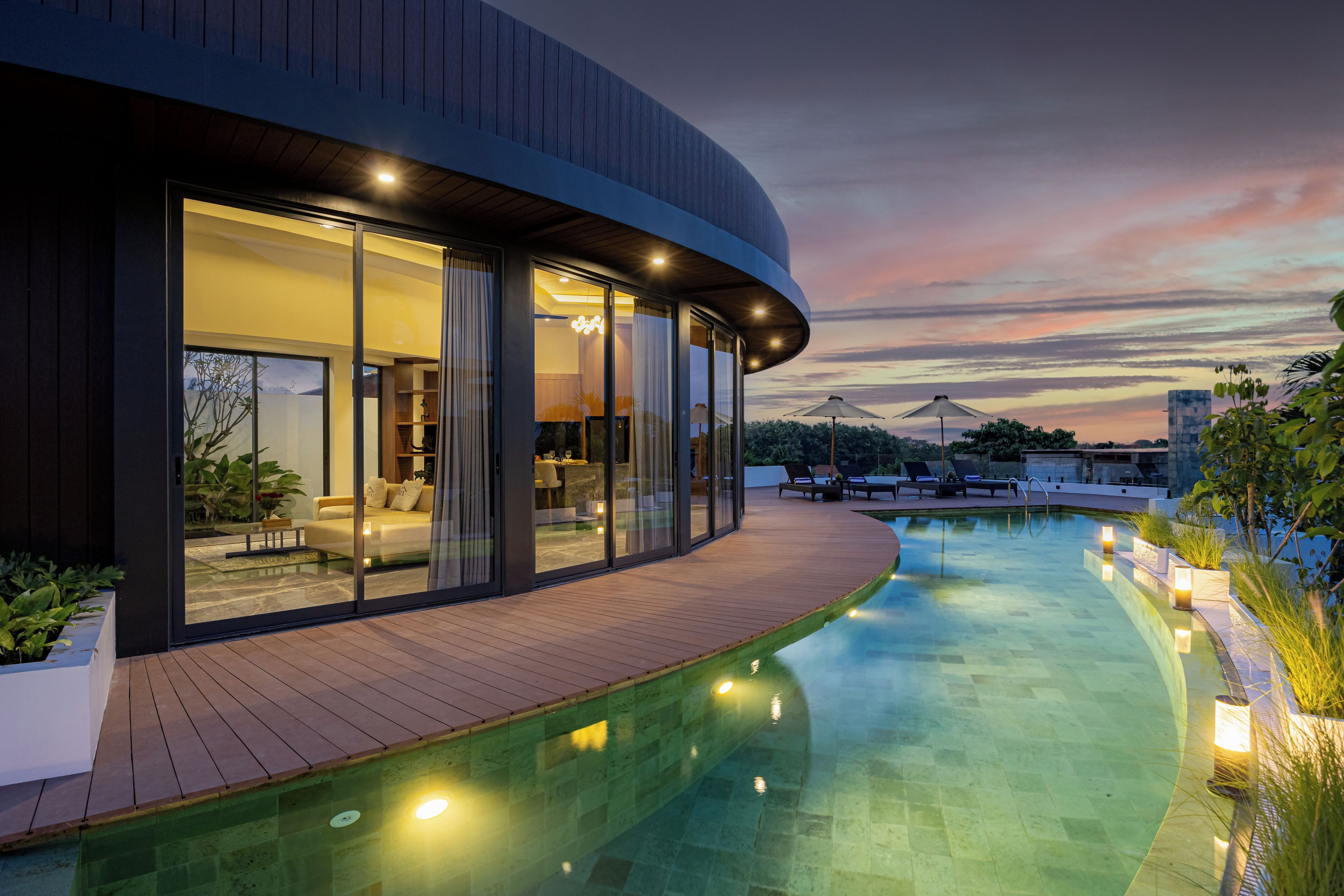 Une maison moderne dotée d’une piscine, de grandes fenêtres et d’une terrasse en bois.
