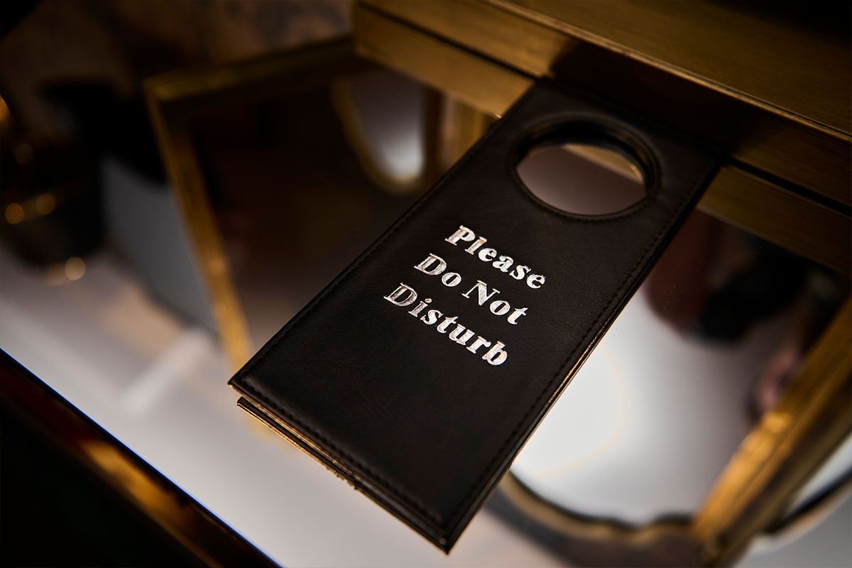 Ein schwarzes Schild mit dem Aufdruck 'Bitte nicht stören', an einer Tür befestigt.