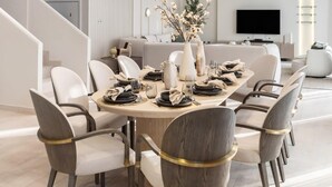 A modern dining area with a round table, chairs, and pendant lighting.
