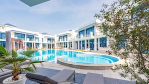 A modern hotel with a central swimming pool, lounge areas, and a view of the surrounding buildings.