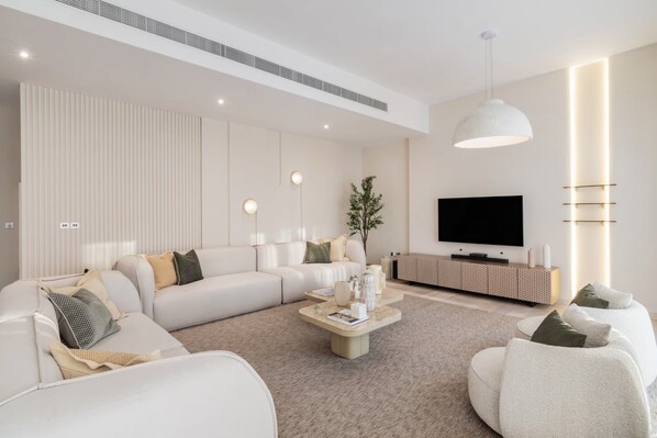 A modern living room with a sectional sofa, a coffee table, a TV, and a minimalist design.