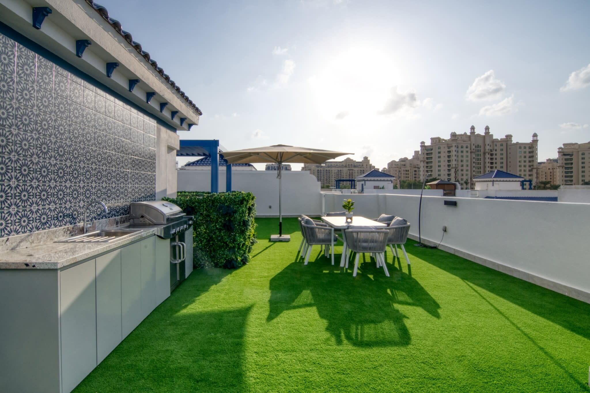 Una terrazza sul tetto con una griglia, un tavolo da pranzo e sedie.