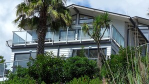 A modern multi-story building with large windows and balconies, surrounded by lush greenery.