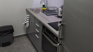Cocina compacta con horno integrado, lavavajillas y fregadero.