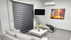 Una sala de estar moderna con un sofá, una mesa de centro, un televisor y un cuadro en la pared.