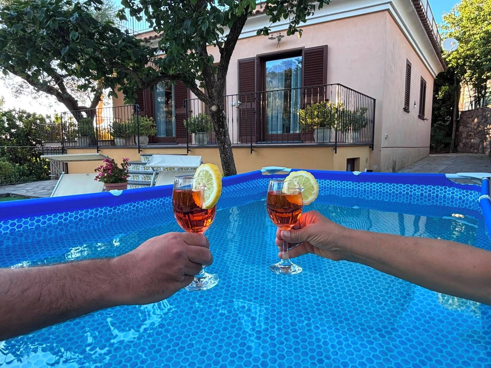 Piscina com padrão de azulejos hexagonais, rodeada por um edifício com varanda e plantas em vasos.