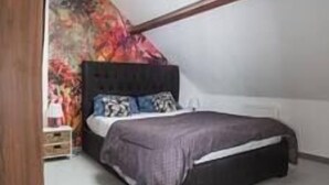 A bedroom with a bed, a window, and a colorful wall.