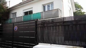 A gated property with a white building, a green fence, and a black gate.