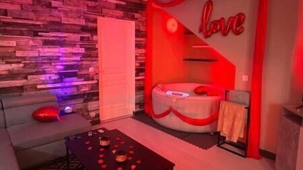 Un dormitorio acogedor con cama, un pequeño rincón de descanso y una pared decorada con un letrero que dice 'love'.