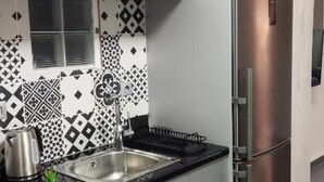 A modern kitchen with white cabinets, a stainless steel refrigerator, and a black countertop. - Ermou Junior Suite by Aesthetic & Luxurious Living (Athens)