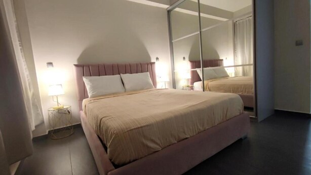 A hotel room with a large bed, a nightstand, a lamp, and a mirror. - Ermou Junior Suite by Aesthetic & Luxurious Living (Athens)