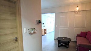 Un salón amplio con una puerta de madera, una mesa de centro redonda, un sofá rojo y una lámpara colgante.