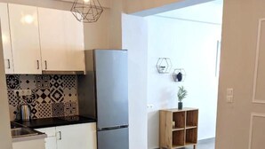 Una cocina moderna con armarios blancos, un refrigerador gris y azulejos de resguardo estampados.
