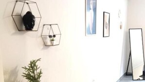Un pasillo con una consola de madera, decoración mural hexagonal y un cartel.