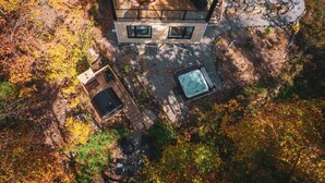 A two-story house with a deck, a hot tub, and a wooden sauna.