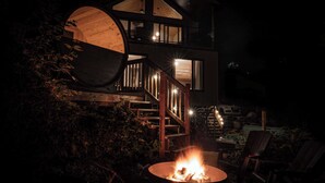A modern house with a circular wooden structure, a fire pit, and outdoor seating.
