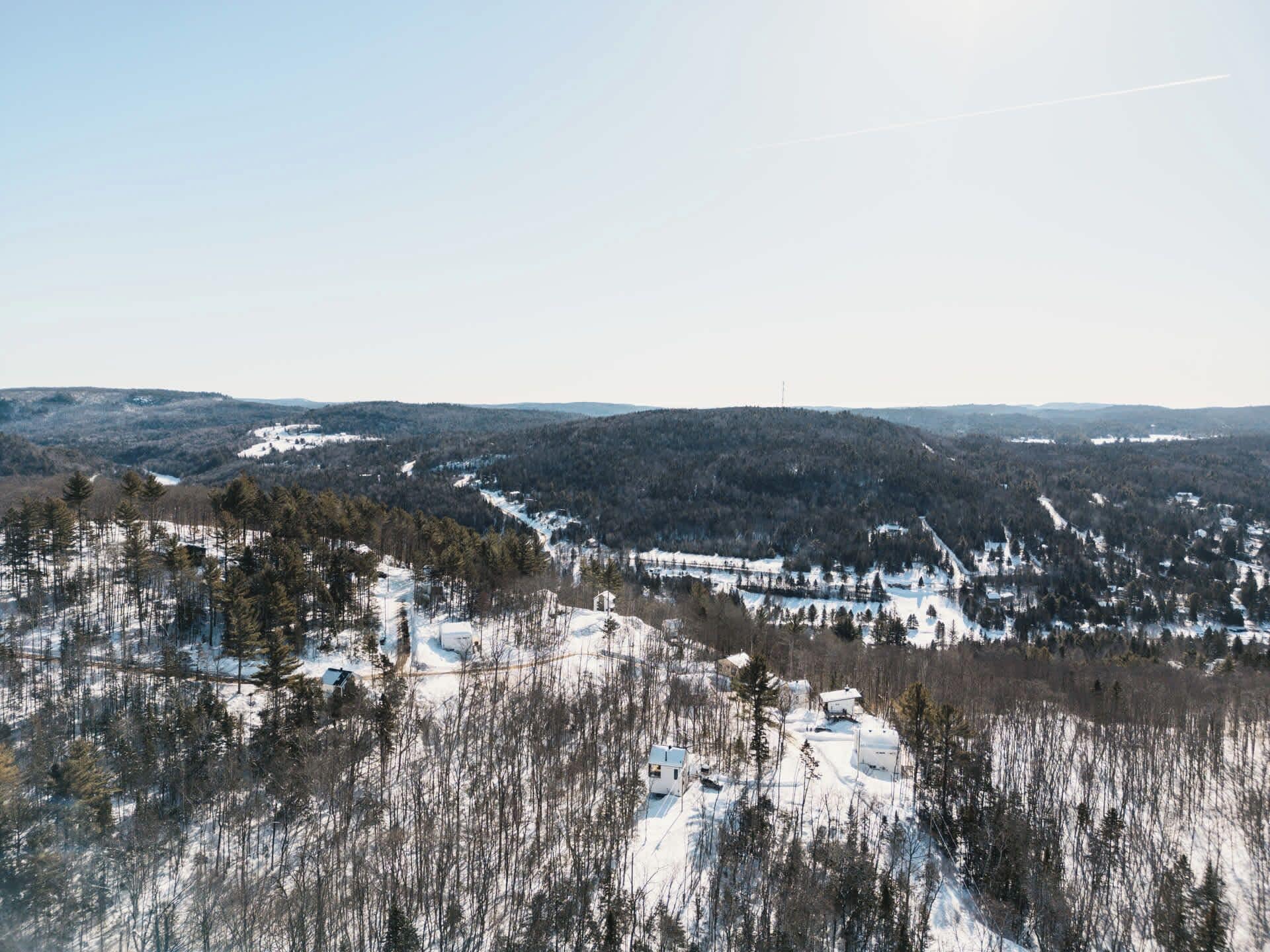 A snow-covered landscape with scattered buildings and dense forests.