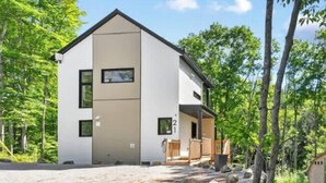 A modern two-story house with a flat roof, a visible number '21' on the side, and a paved driveway leading to the entrance. - Le Sören - Sauna, Terrace, Fireplace & River (Sainte-Béatrix)