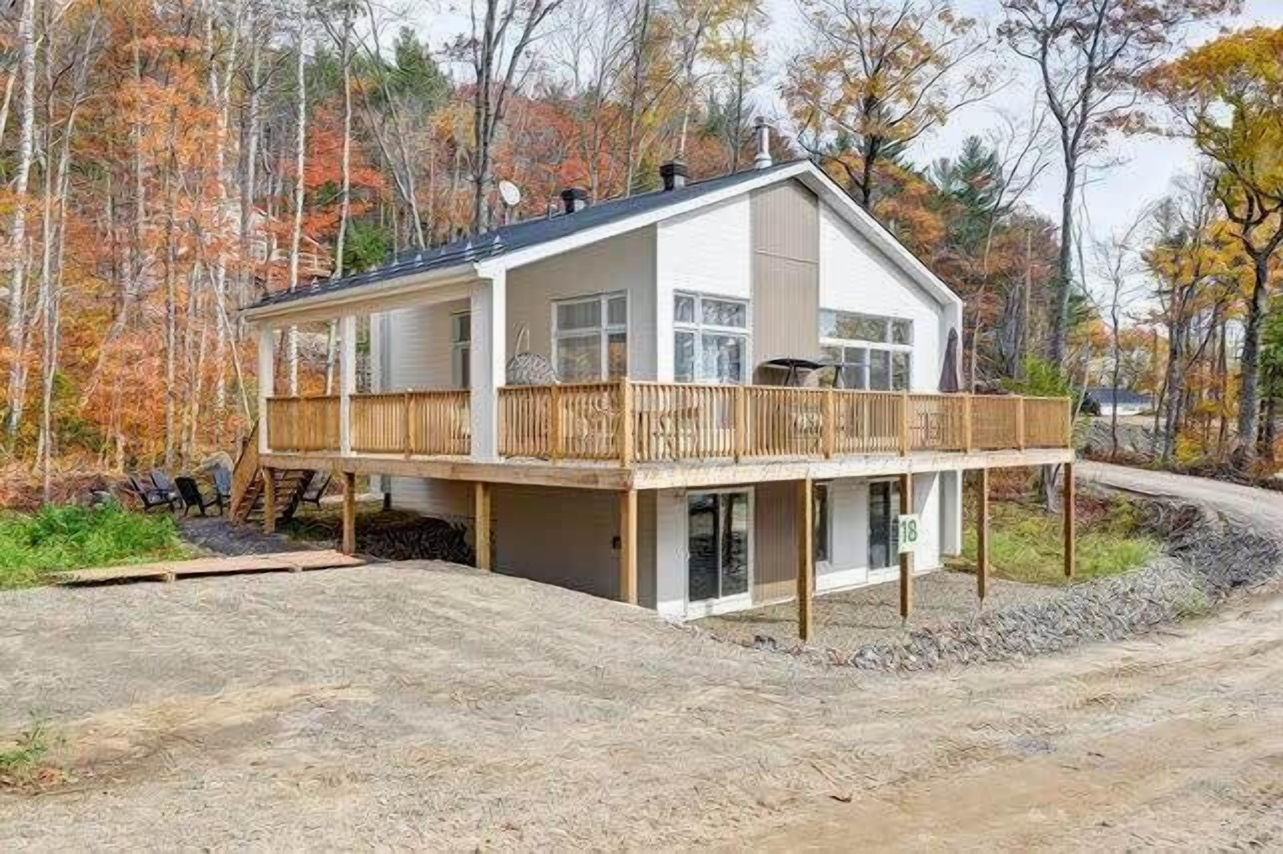 Eine zweistöckige Holzhütte mit einem Balkon, umgeben von einem Wald im Herbstlaub.