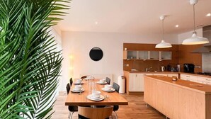 A modern kitchen with wooden cabinets, a central island, and pendant lighting. - Lovely Spacious Apartment with Hydro & SECC (Glasgow City)