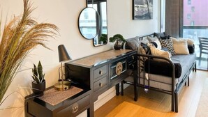 Un dormitorio moderno con cama, mesita de noche, cómoda y ventanas amplias.