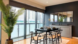 Un comedor moderno con un ventanal grande, una planta en maceta y una mesa de comedor preparada para cuatro comensales.