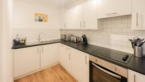 A modern kitchen with white cabinets, a black countertop, and a stainless steel oven. - Cozy 1 bed Blythswood Apartment (Glasgow City)