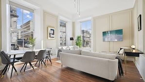Una sala de estar moderna con sofá, mesa de comedor, sillas y televisor.