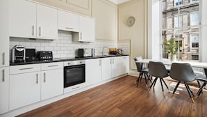 Una cocina moderna con armarios blancos, encimera negra y un comedor con mesa y sillas.