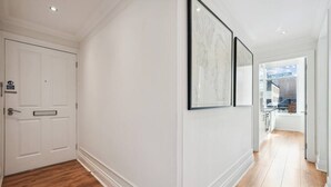 A hallway with white walls, wooden flooring, and a door with a handle.