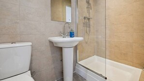 A bathroom with a toilet, sink, and glass-enclosed shower area.